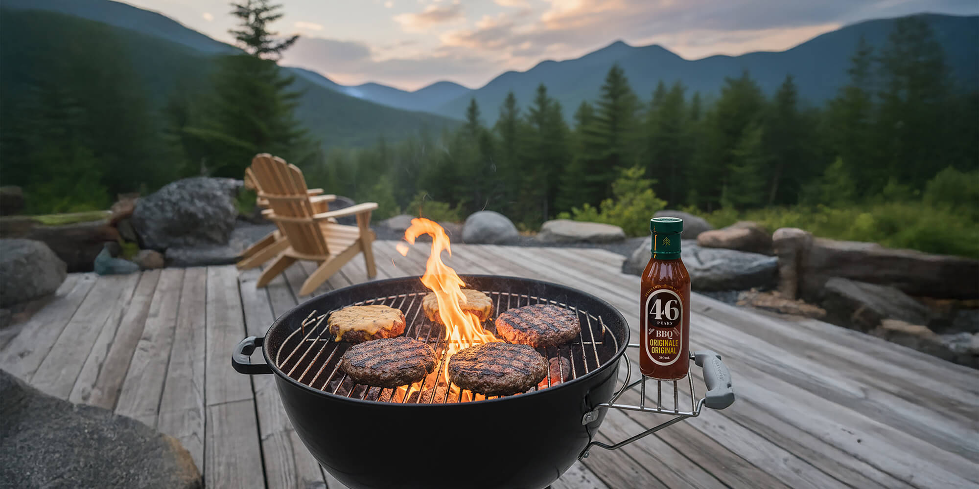 Barbecue grill with burgers and a bottle of 46 Peaks BBQ sauce on a wooden deck with a mountainous background