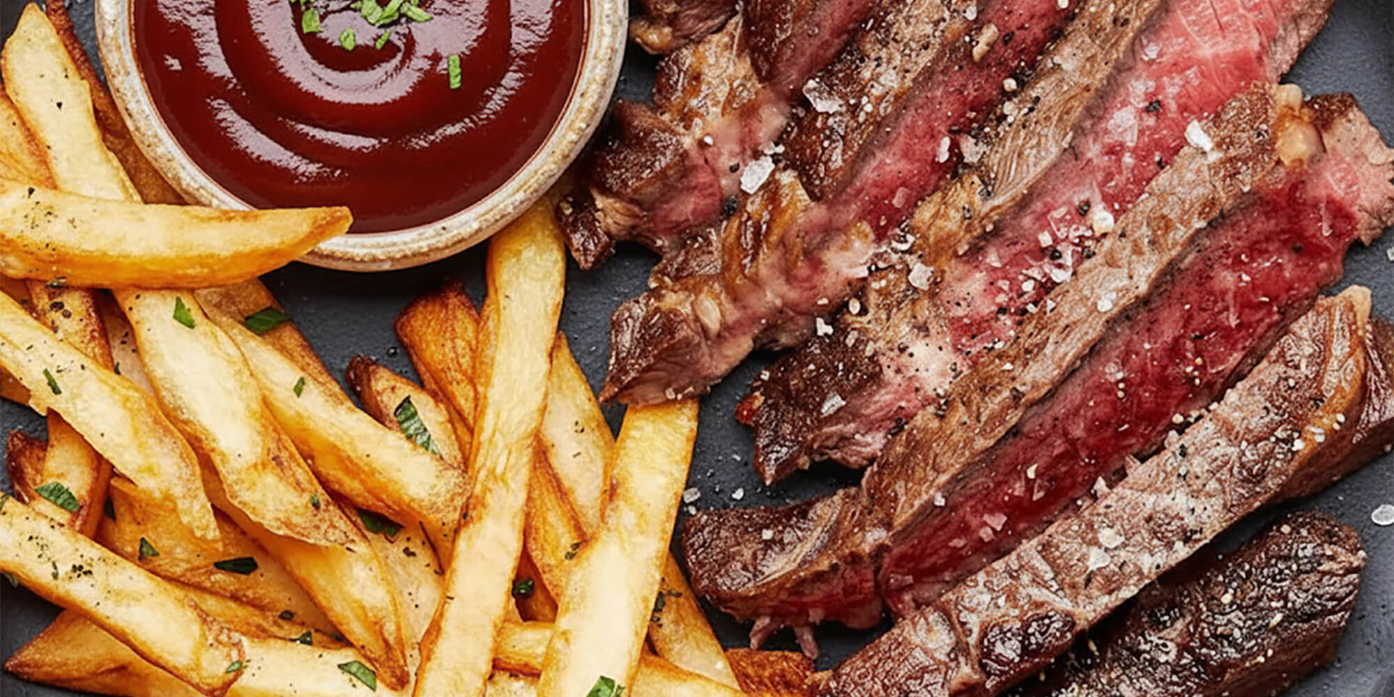 Steak with fries and a side of sauce on a plate