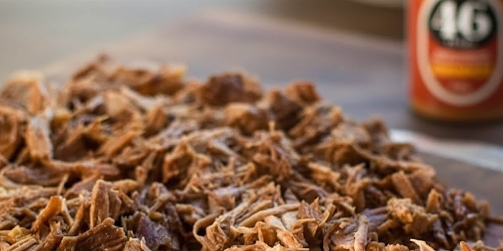 Shredded pork on a tray with a bottle of 46 peaks in the background